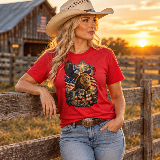 Blonde model wearing the red graphic tee at a farm fence at sunset